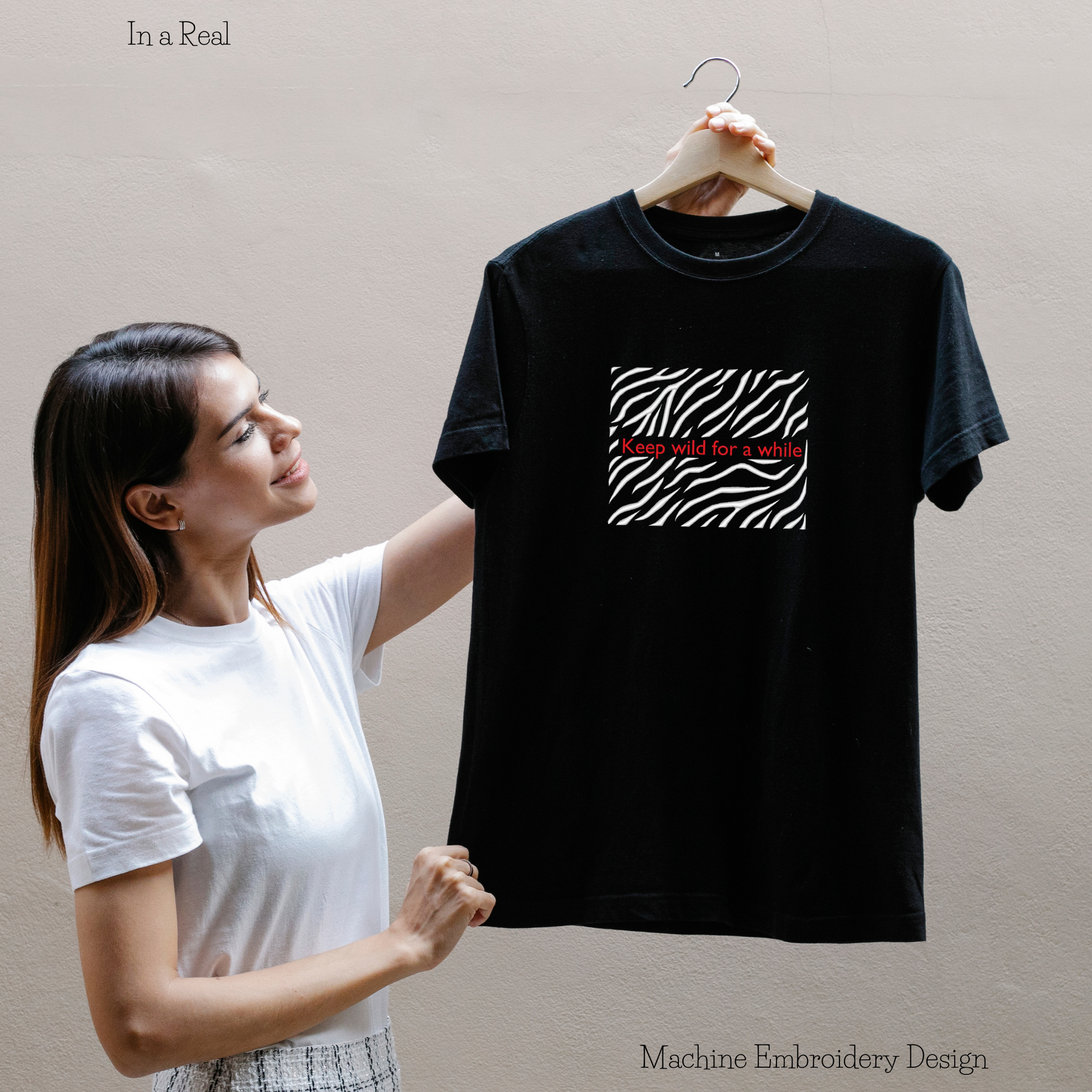 A machine embroidery design featuring the phrase 'Keep Wild for a While' with a captivating zebra print motif is displayed on a T-shirt