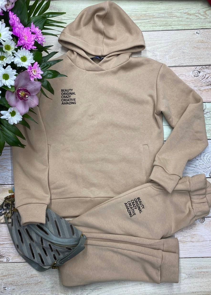 Machine embroidery design featuring the text "Beauty Original Creazy Creative Amazing" displayed on a sweatsuit